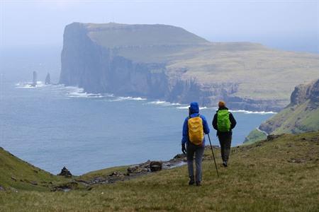 Hike op de Faeröer eilanden met Risin en Kellingin rotsformaties op de achtergrond